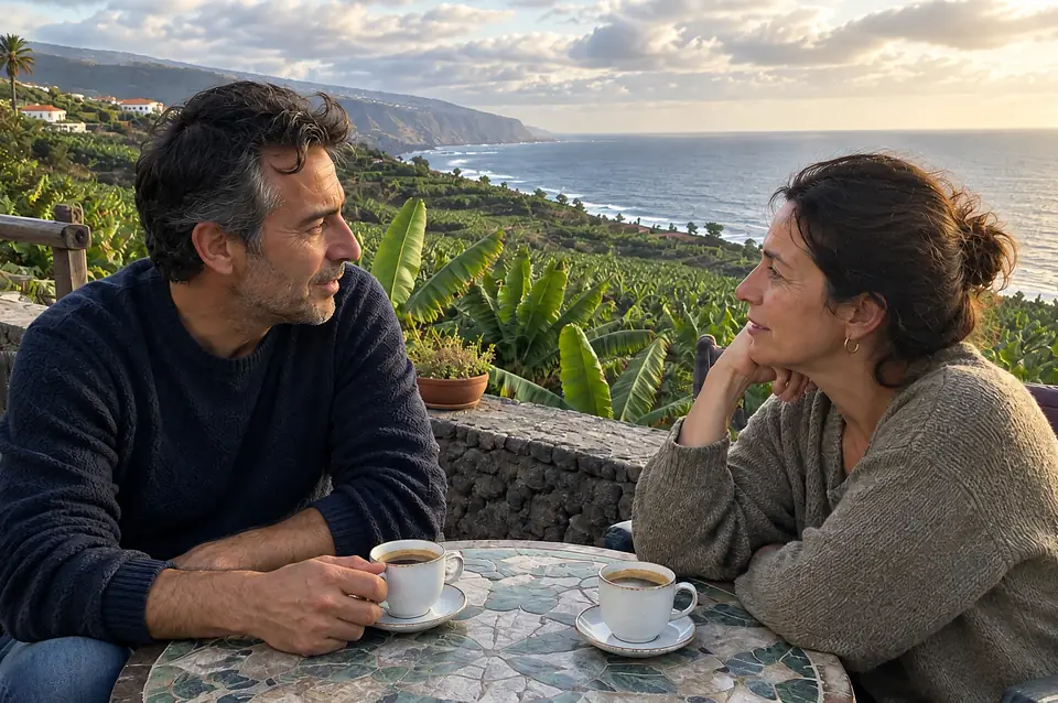 Pareja conversando en una terraza con plataneras y el mar al fondo
